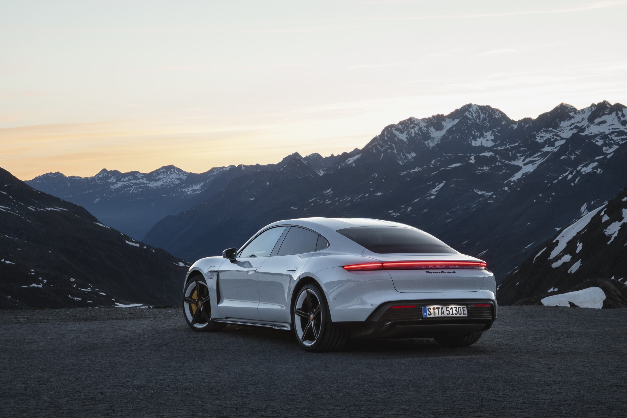 White Porsche Taycan rear and left side with mountain background